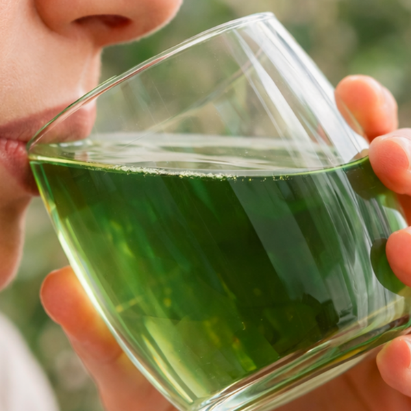 Green drink in a glass being held